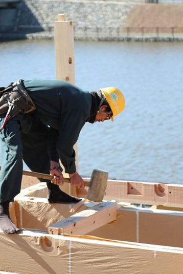 住宅の骨組みを木槌で叩く大工